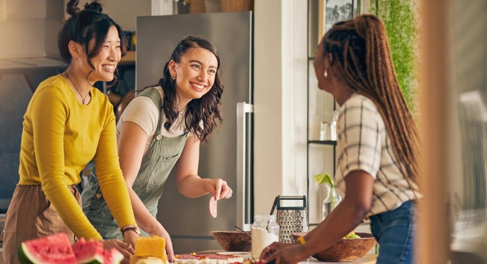 three women smiling and laughing around a table